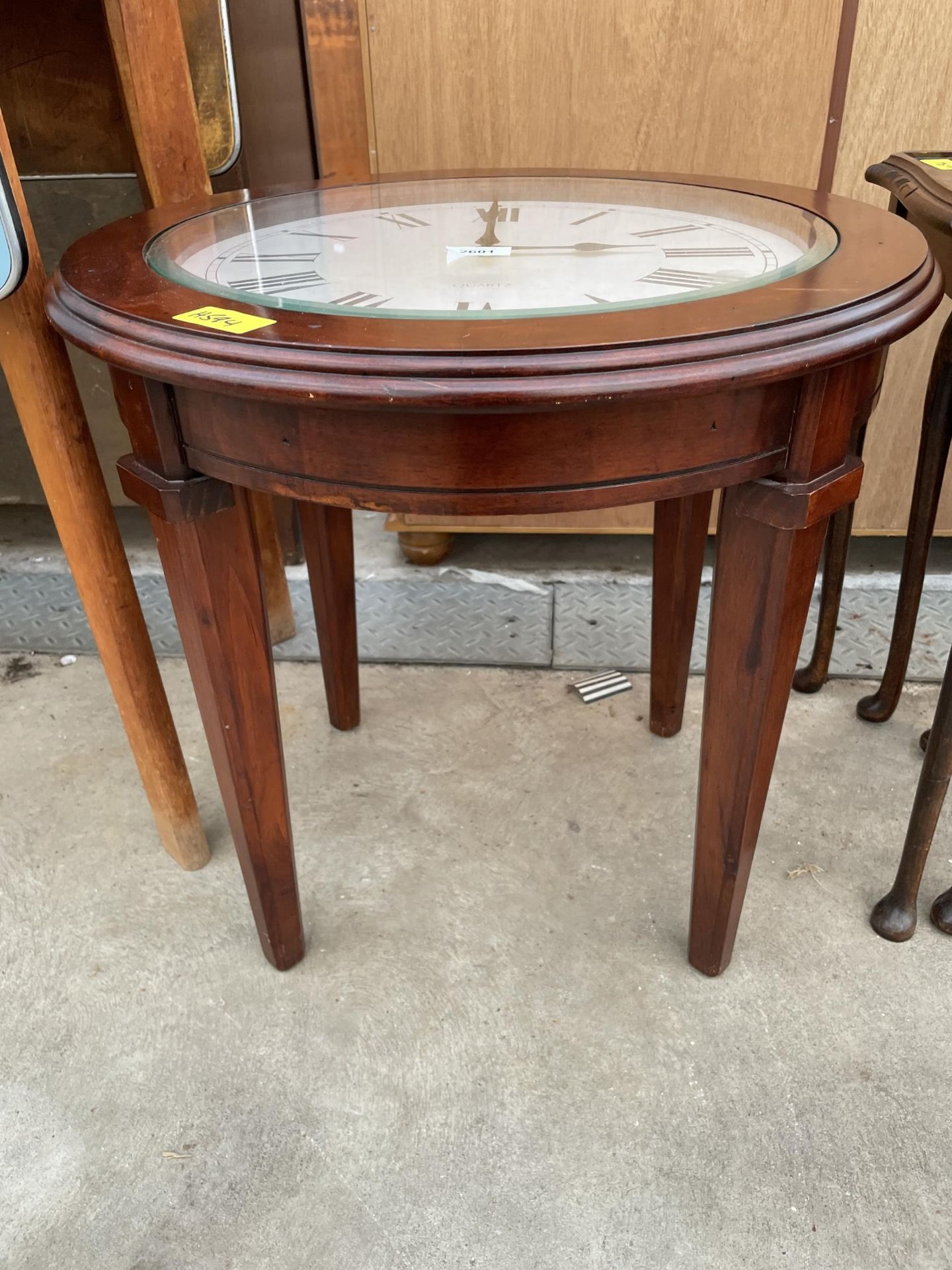 A 22" DIAMETER OCCASIONAL TABLE, THE GLASS TOP REVEALING QUARTZ CLOCK WITH ROMAN NUMERALS - Image 2 of 2