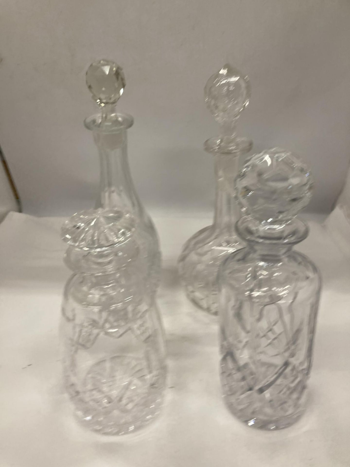 FOUR CUT GLASS DECANTERS OF VARYING SHAPES