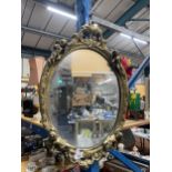 A VINTAGE GILT FRAMED OVAL MIRROR WITH CHERUB DECORATION, 43CM X 68CM