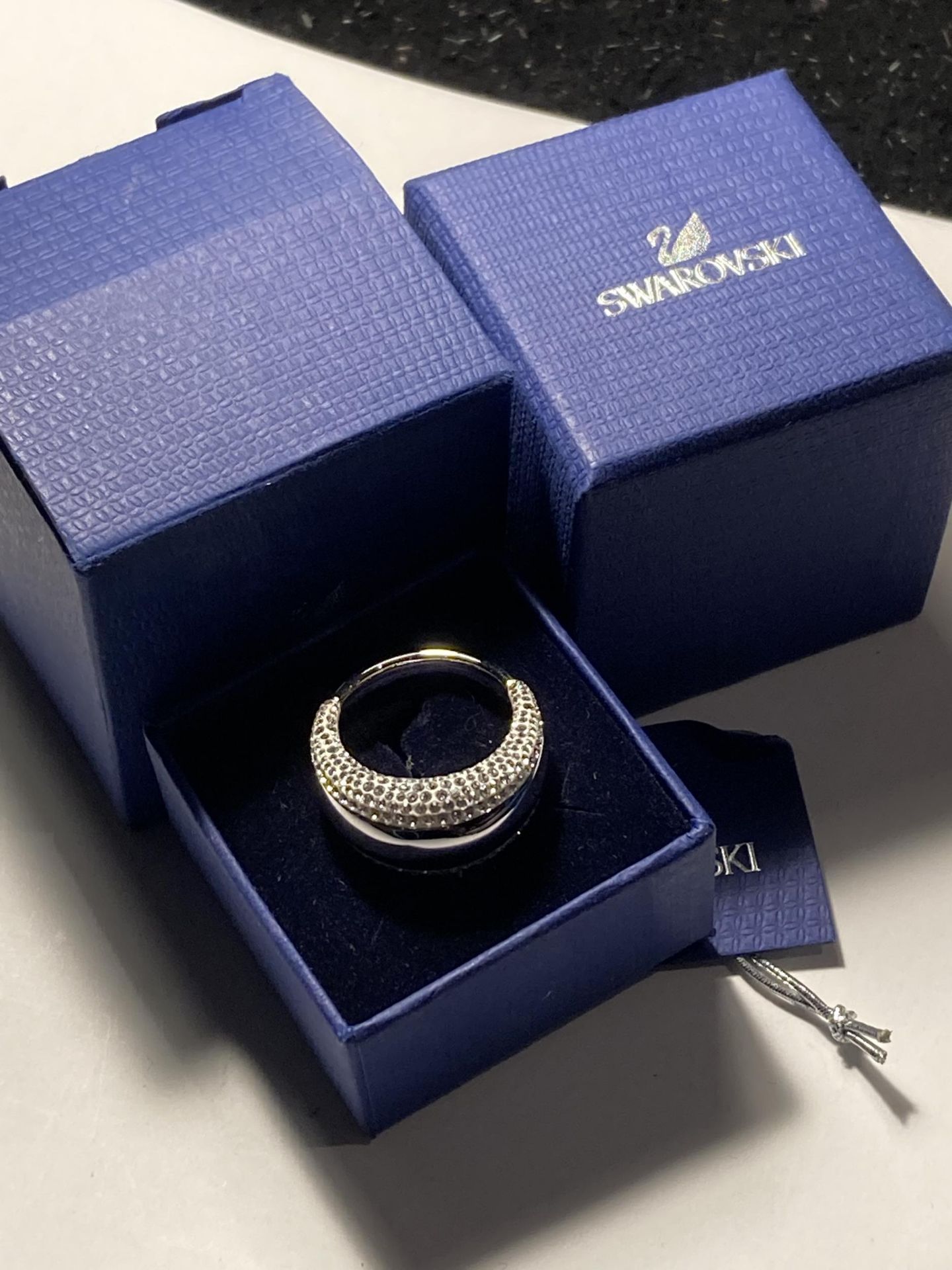 A SWAROVSKI CRYSTAL RING WITH LABEL IN A PRESENTATION BOX WITH SLEEVE SIZE R