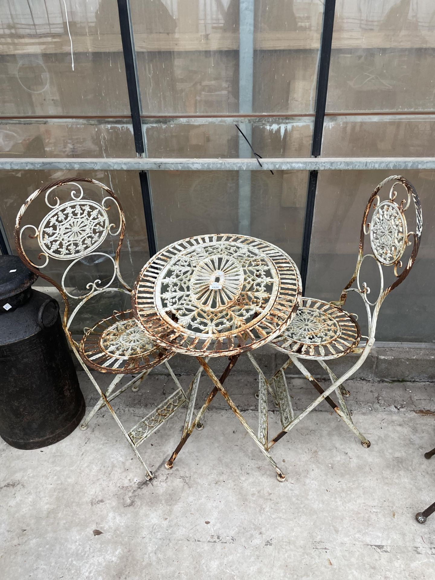 A VINTAGE FOLDING METAL BISTRO TABLE AND TWO CHAIRS