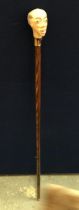A VINTAGE WOODEN WALKING STICK WITH PAINTED FIGURAL HEAD DESIGN, SIGNED WH, WITH COPPER FERRULE