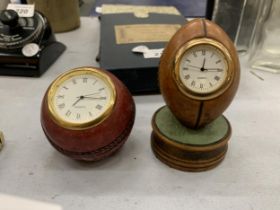 TWO HISTORY CRAFT DESK CLOCKS IN THE FORM OF A CRICKET BALL AND RUGBY BALL