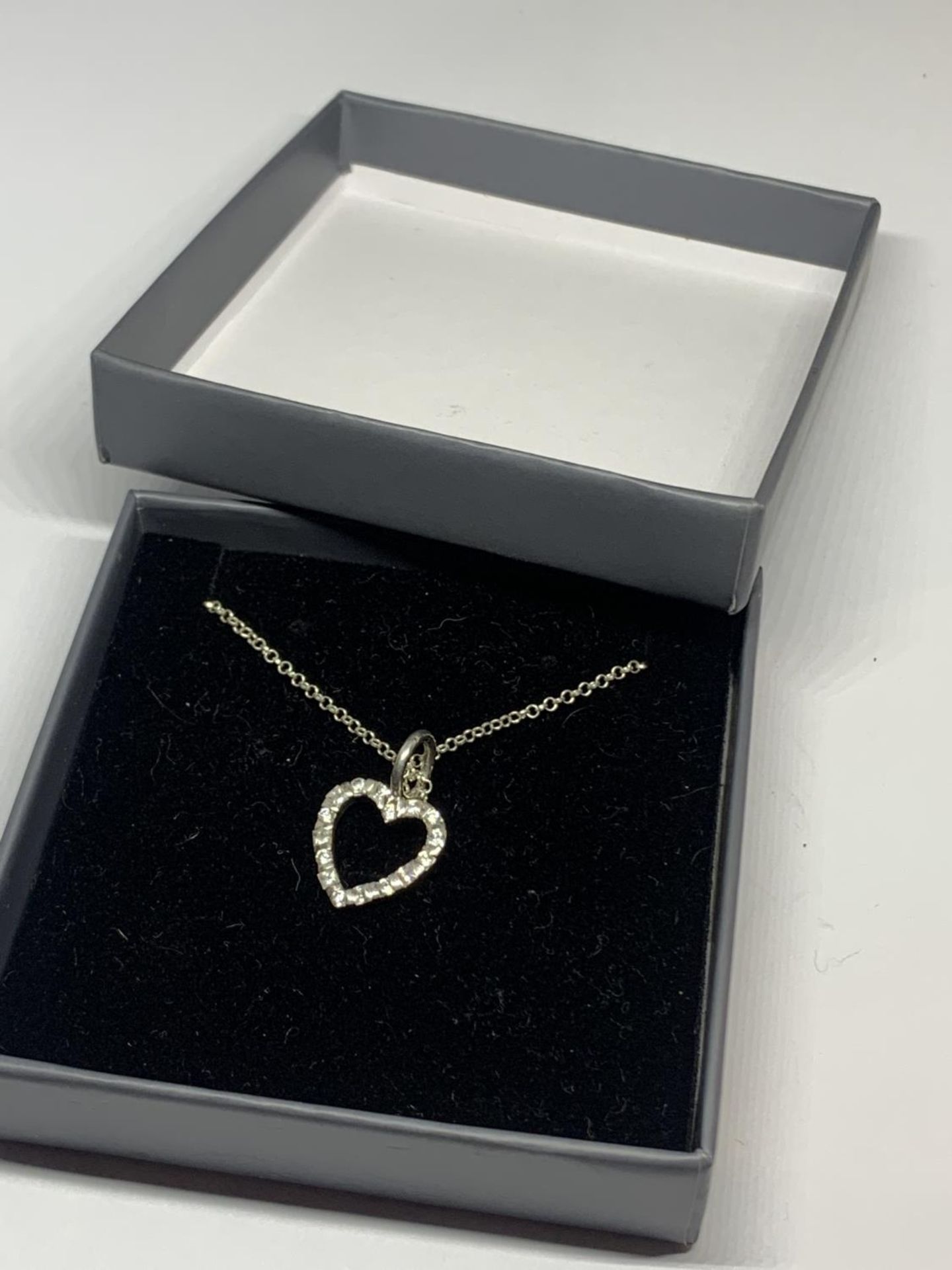 A SILVER BOXED NECKLACE WITH CLEAR STONE HEART PENDANT