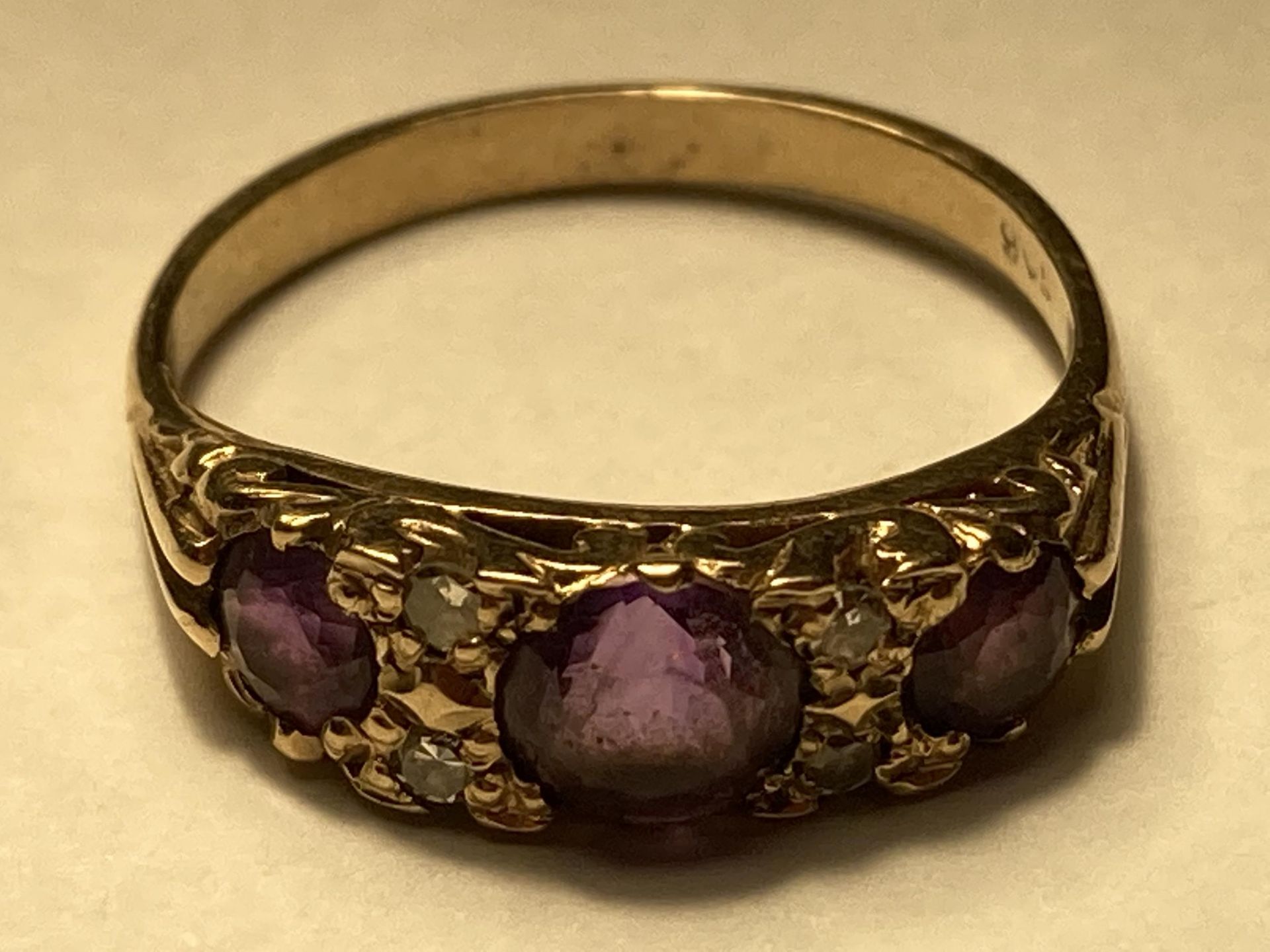 A 9 CARAT GOLD RING WITH THREE IN LINE AMETHYSTS AND DIAMONDS SIZE O