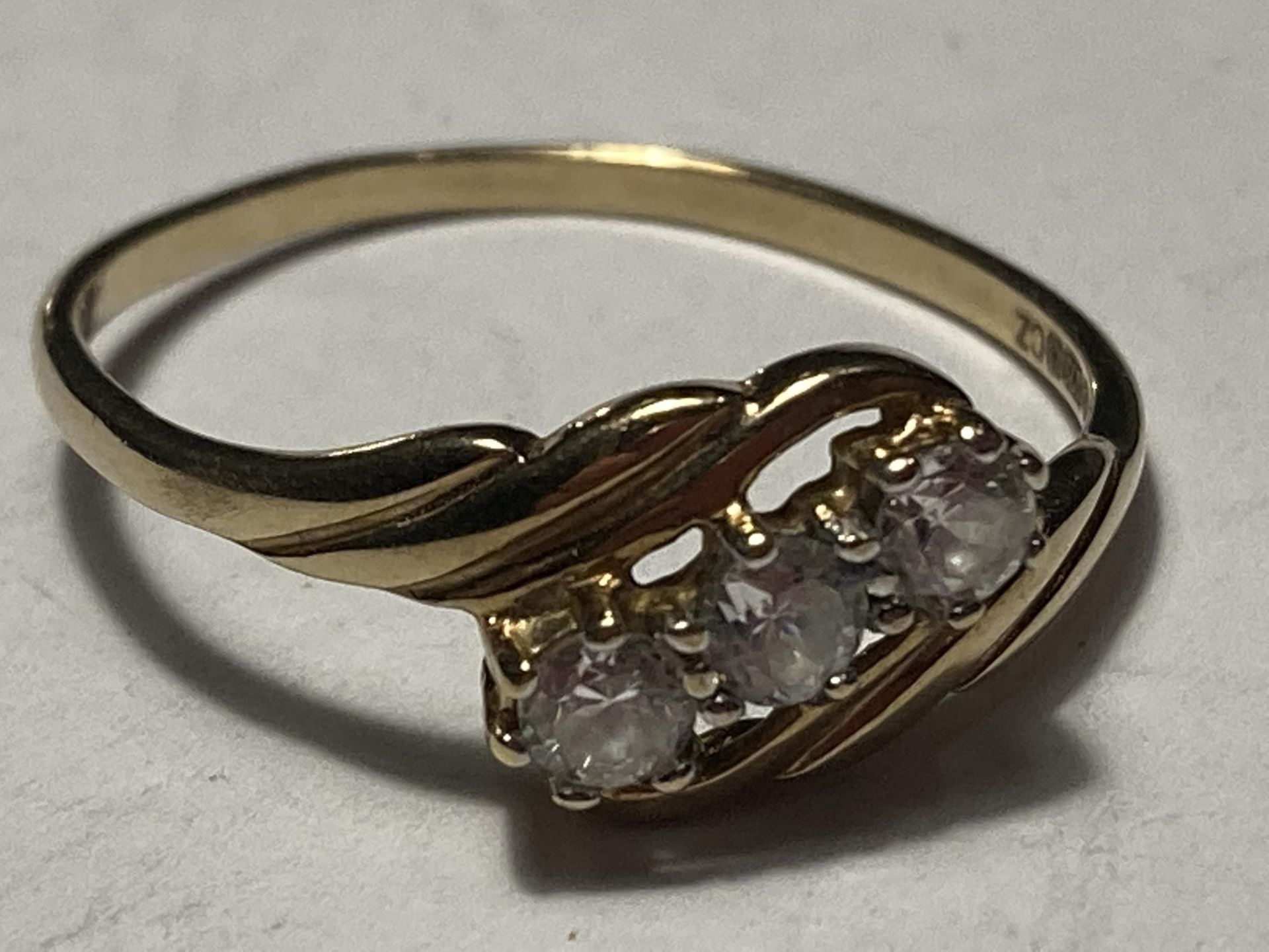 A 9 CARAT GOLD RING WITH THREE CUBIC ZIRCONIAS ON A TWIST SIZE Q/R