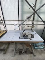 A BROTHER INDUSTRIAL OVERLOCKER SEWING MACHINE WITH TREADLE BASE AND ANGLE POISE LAMP
