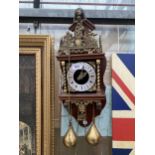 A HEAVILY DECORATIVE AND ORNATE WOODEN AND BRASS WALL CLOCK WITH WEIGHTS
