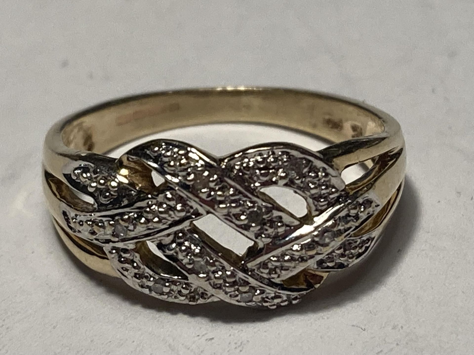 A 9 CARAT GOLD RING WITH DIAMONDS IN A CROSSOVER DESIGN SIZE M