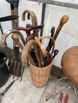 A WICKER STICK STAND AND AN ASSORTMENT OF WALKING STICKS