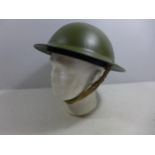 A MID 20TH CENTURY GREEN PAINTED METAL BRITISH HELMET AND LINER