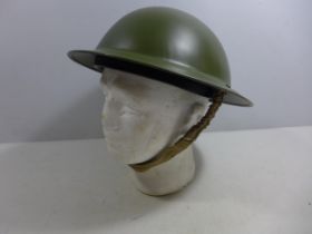 A MID 20TH CENTURY GREEN PAINTED METAL BRITISH HELMET AND LINER