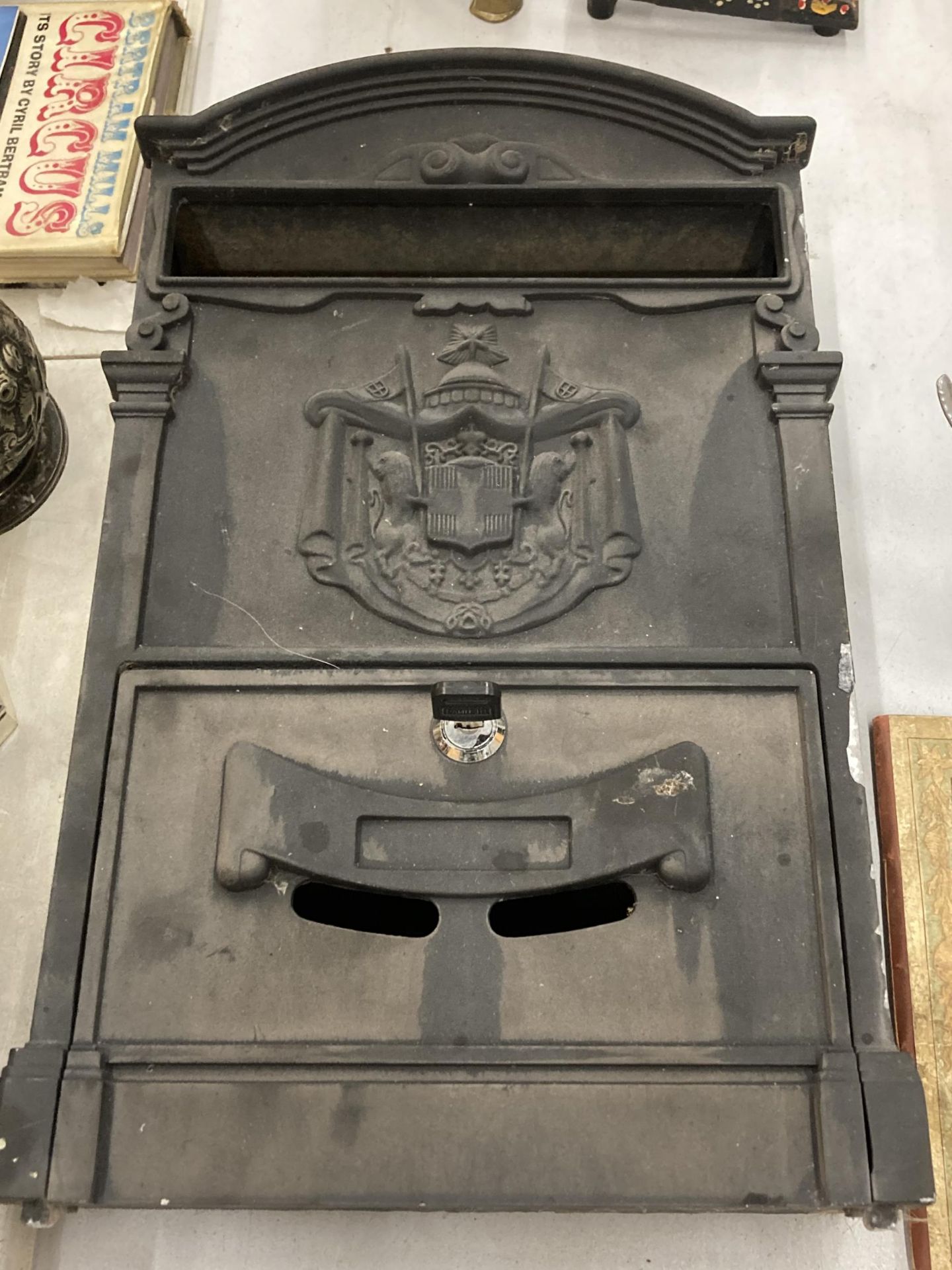 A BLACK METAL WALL MOUNTED LETTER BOX WITH COAT OF ARMS AND KEY