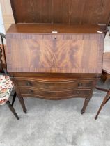 A MAHOGANY AND CROSSBANDED BUREAU ON TURNED AND FLUTED LEGS, 30" WIDE