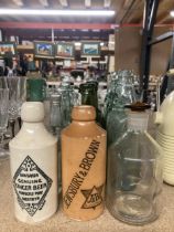 A COLLECTION OF VINTAGE GLASS BOTTLES WITH ADVERTISING ON THEM PLUS TWO STONE ONES