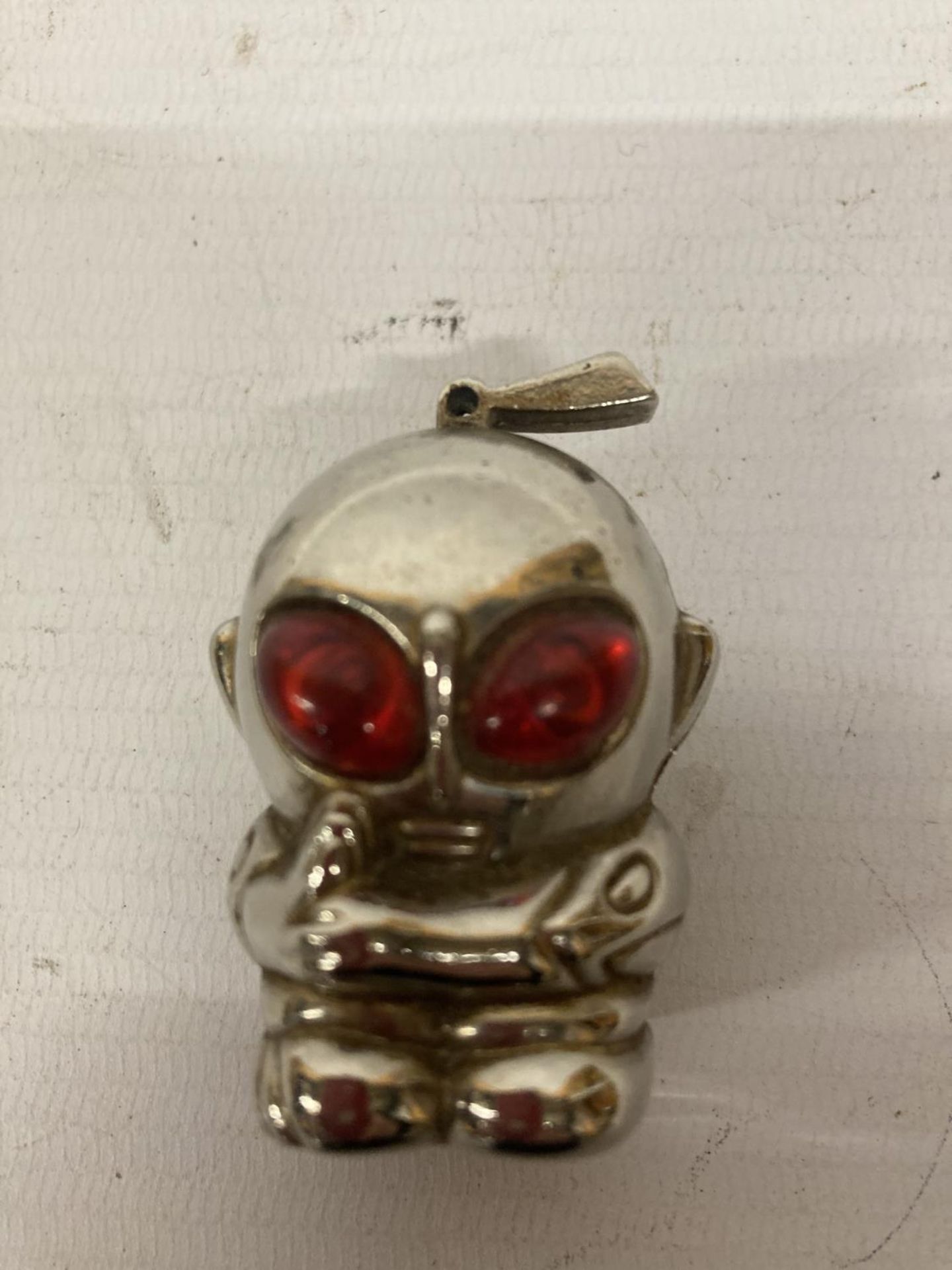 A VINTAGE WHITE METAL LIGHTER IN THE SHAPE OF AN ALIEN WITH RED EYES, HEIGHT 5CM