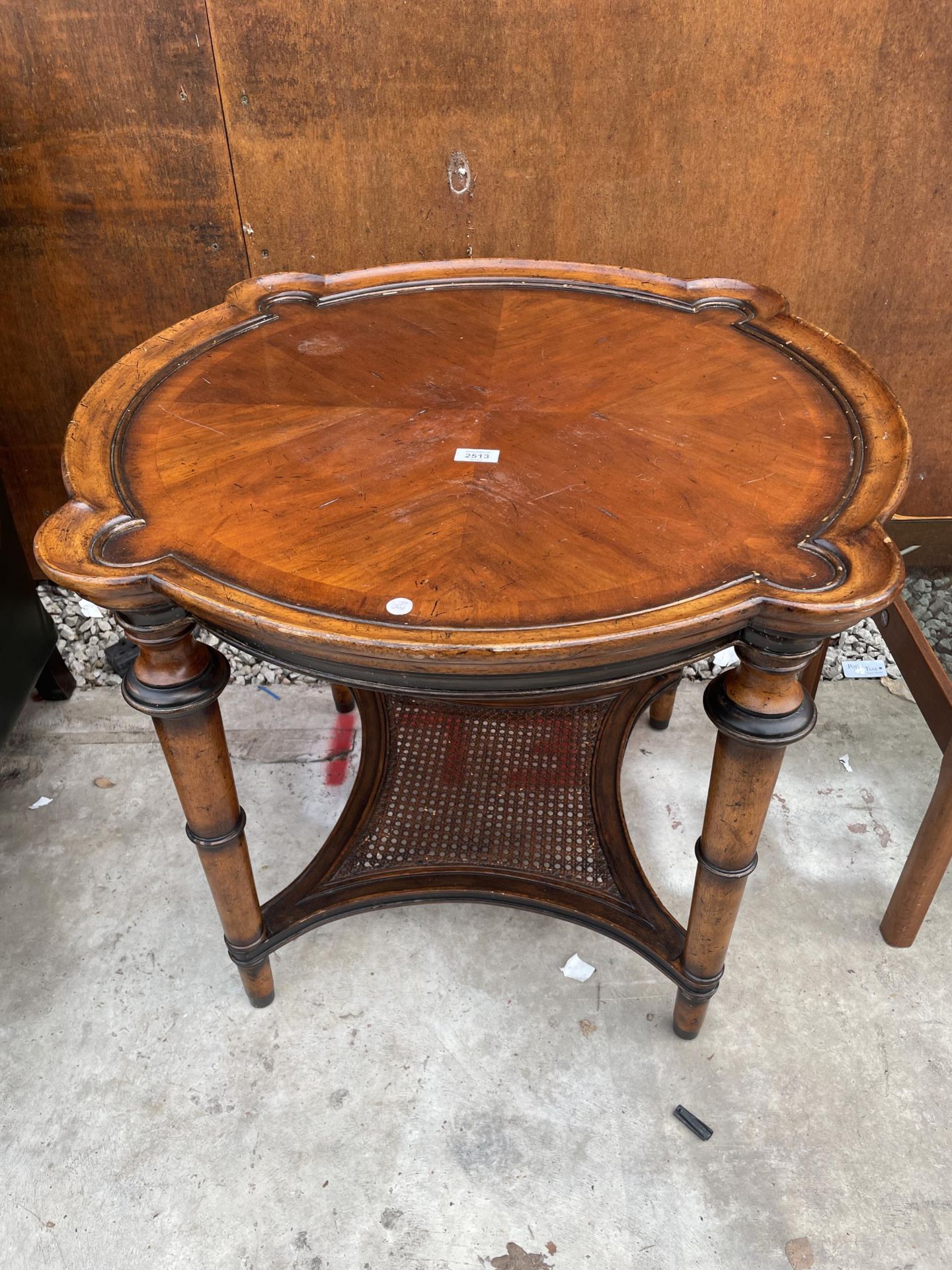 AN FBIS FURNITURE HARDWOOD TWO TIER OCCASIONAL TABLE WITH SHAPED TOP AND CANE LOWER SHELF ON