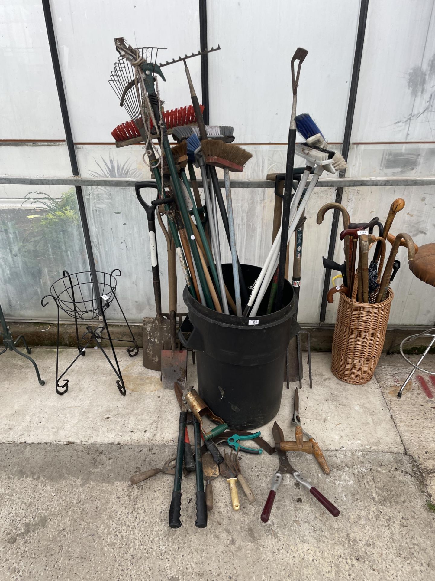 A PLASTIC BIN CONTAINING A LARGE QUANTITY OF GARDEN TOOLS TO INCLUDE FORKS AND SPADES ETC