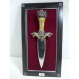 A FANTASY DAGGER MOUNTED ON A WOODEN FRAME, 22CM DOUBLE EDGED BLADE, GRIP WITH DRAGONS HOLDING