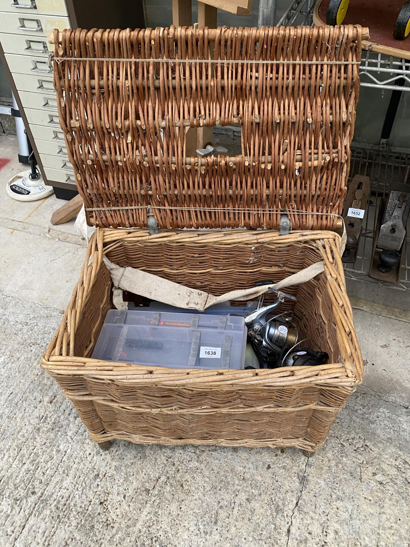 A WICKER TACKLE BASKET AND AN ASSORTMENT OF FISHING TACKLE TO INCLUDE REELS AND FLOATS ETC