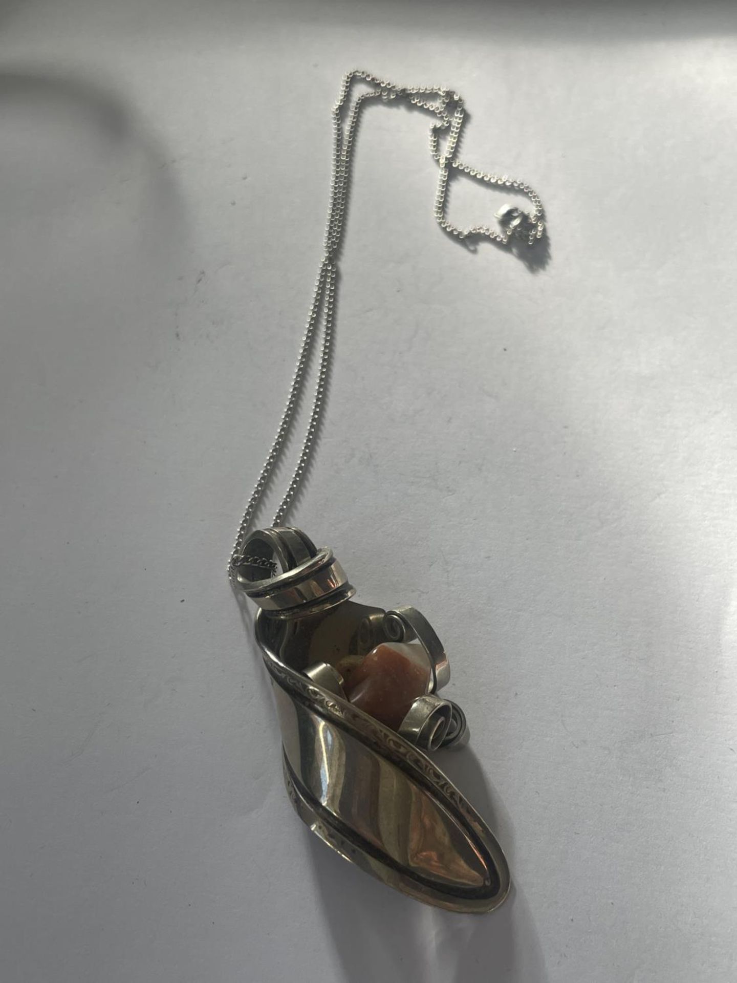 AN ORNATE WHITE METAL SPOON AND AGATE PENDANT
