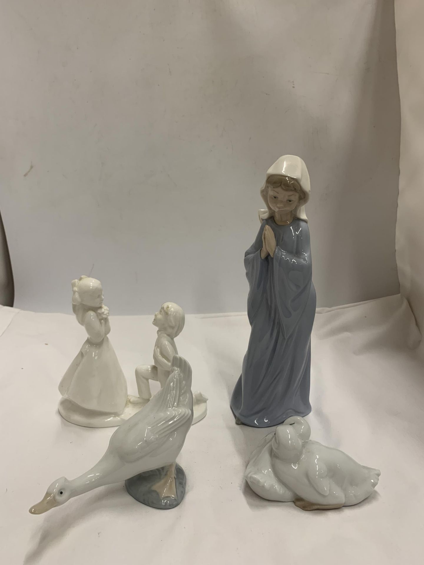 A GROUP OF FOUR FIGURES - NAO LLADRO GIRL AND GEESE AND A ROYAL DOULTON IMAGES FIGURE