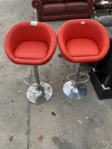 A PAIR OF BRIGHT ORANGE PUMP STOOLS ON POLISHED CHROME PEDESTALS AND BASES