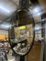 AN ORNATE BLACK FRAMED OVAL WALL MIRROR