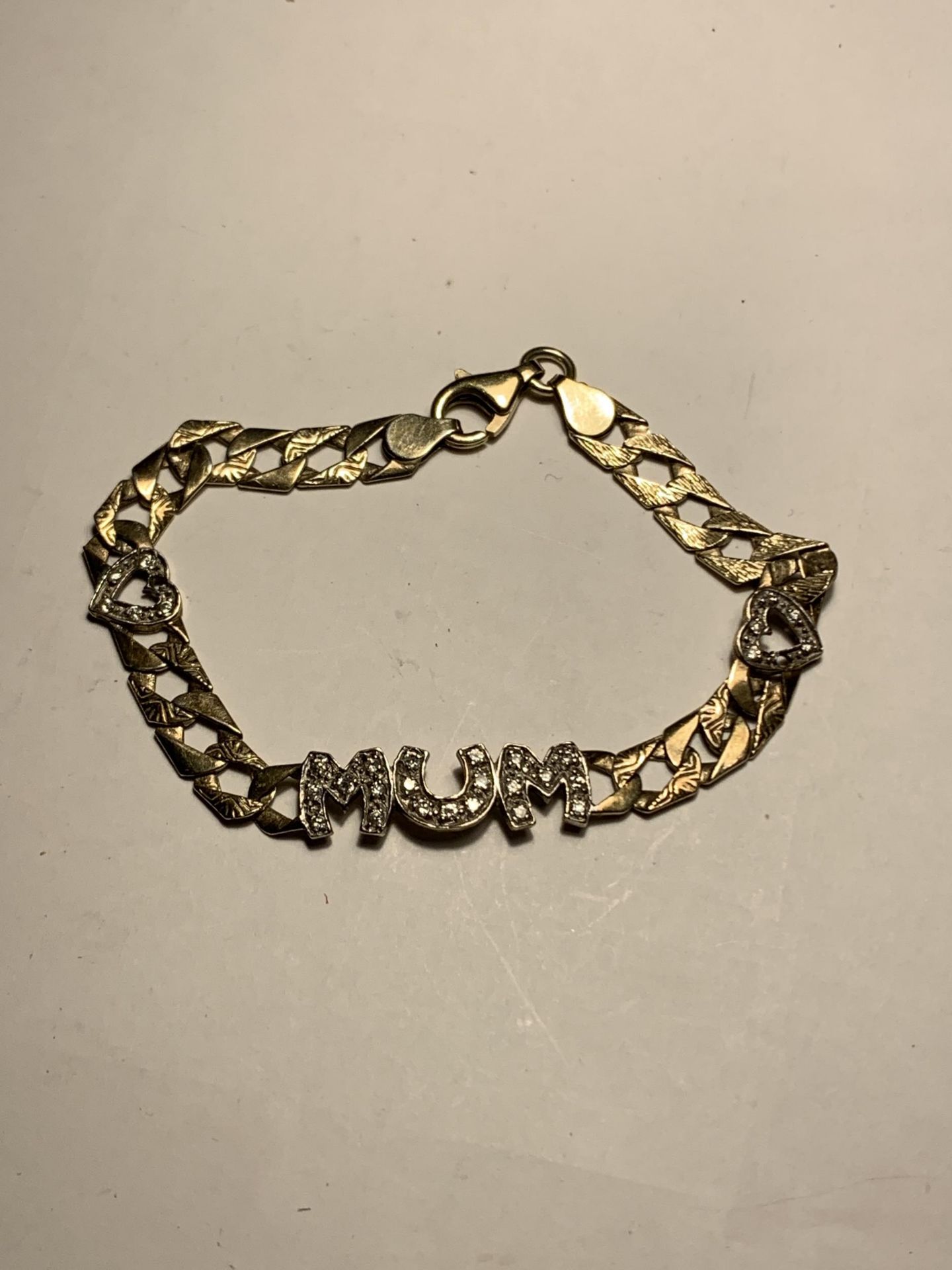 A HEAVY SILVER GILT, STAMPED 925 CURB LINK BRACELET WITH MUM AND TWO HEARTS IN CLEAR STONES