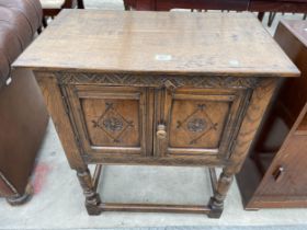 AN OAK JACOBEAN STYLE TWO DOOR CUPBOARD ON OPEN BASE WITH TURNED LEGS, 26" WIDE