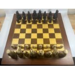 A VINTAGE LEWIS CHESSMEN CHESS SET MODELLED AS MEDIEVAL FIGURES ON AN INLAID WOODEN BOARD, KING
