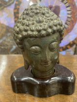 A BRONZE EFFECT BUDDHA HEAD MODEL ON WOODEN BASE