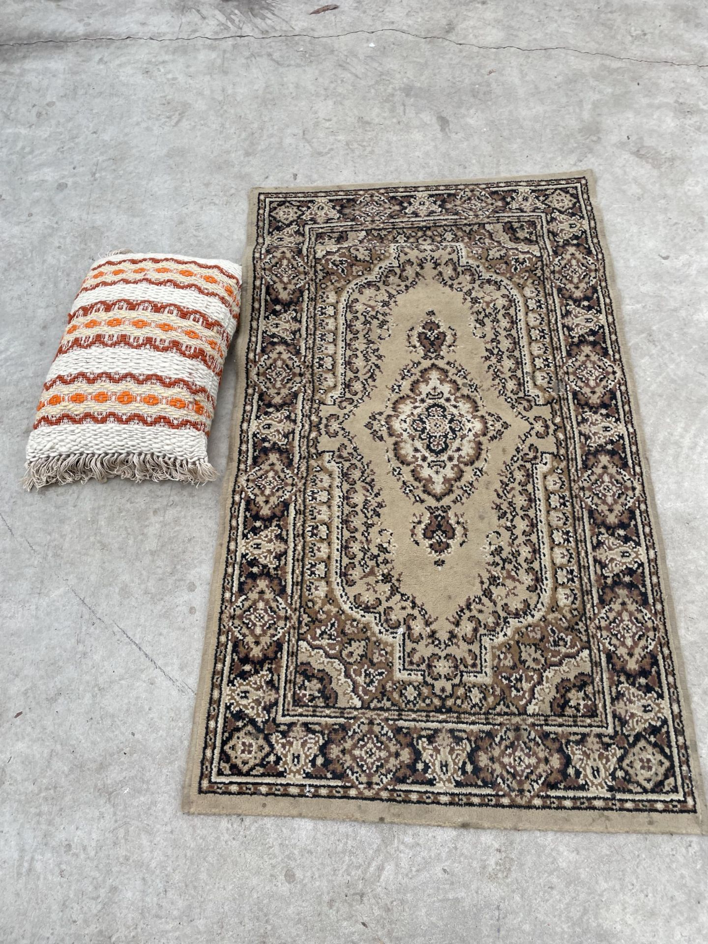 A SMALL CREAM PATTERNED RUG AND A CUSHION