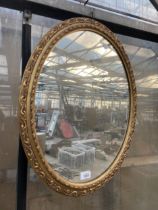 A DECORATIVE OVAL GILT FRAMED WALL MIRROR