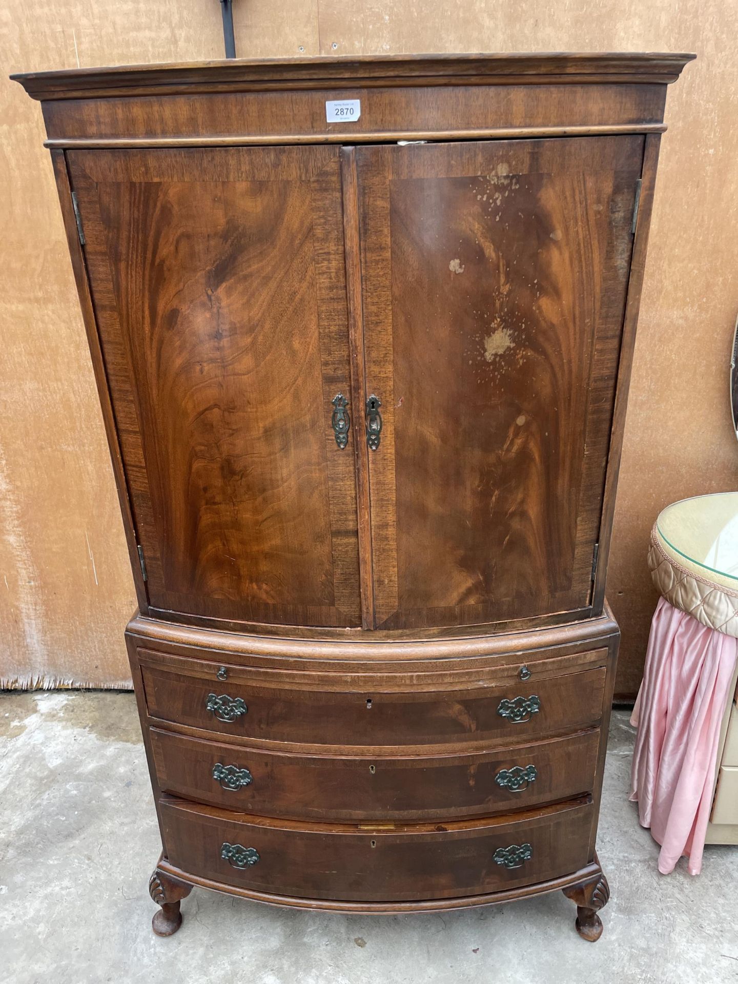 A 19TH CENTURY MAHOGANY AND CROSSBANDED BOWFRONTED PRESS STYLE CUPBOARD WITH THREE GRADUATED DRAWERS