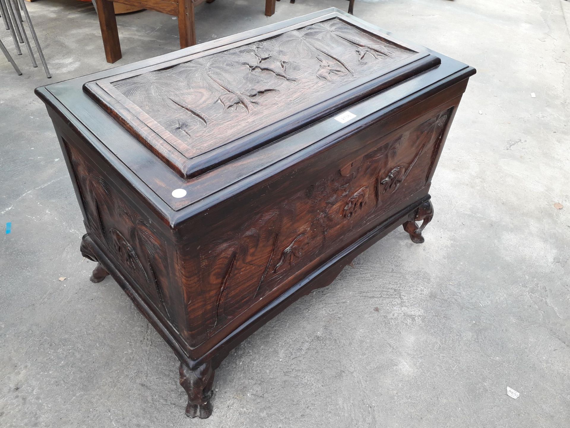 AN ORIENTAL HARDWOOD BLANKET CHEST PROFUSELY CARVED WITH ELEPHANTS AND TREES, COMPLETE WITH LIFT-OUT