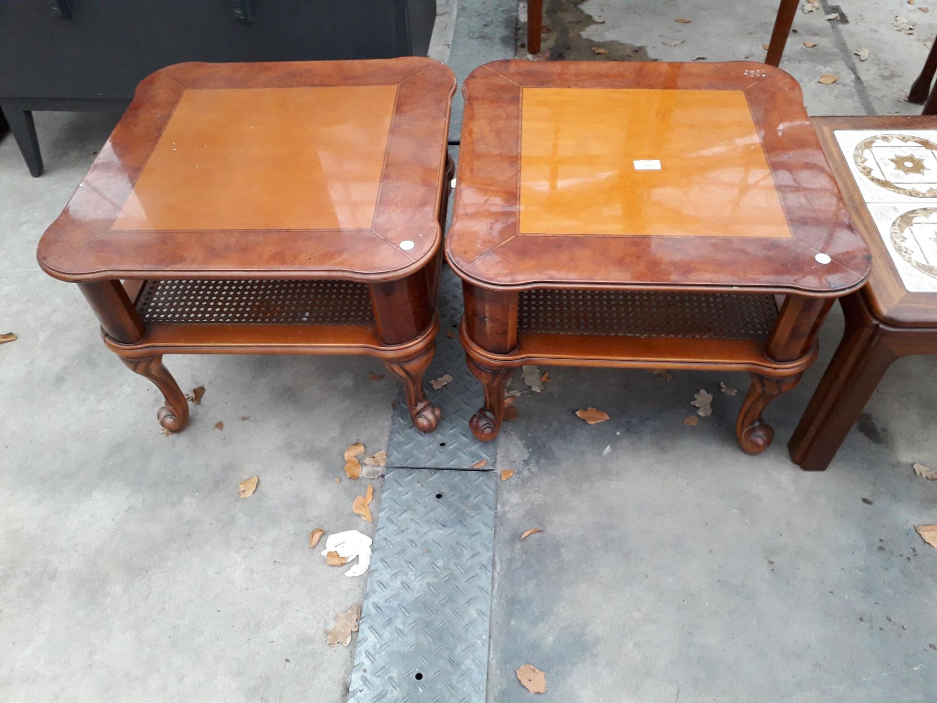 A PAIR OF BURR WALNUT LAMP TABLES WITH CANE MAGAZINE SHELF