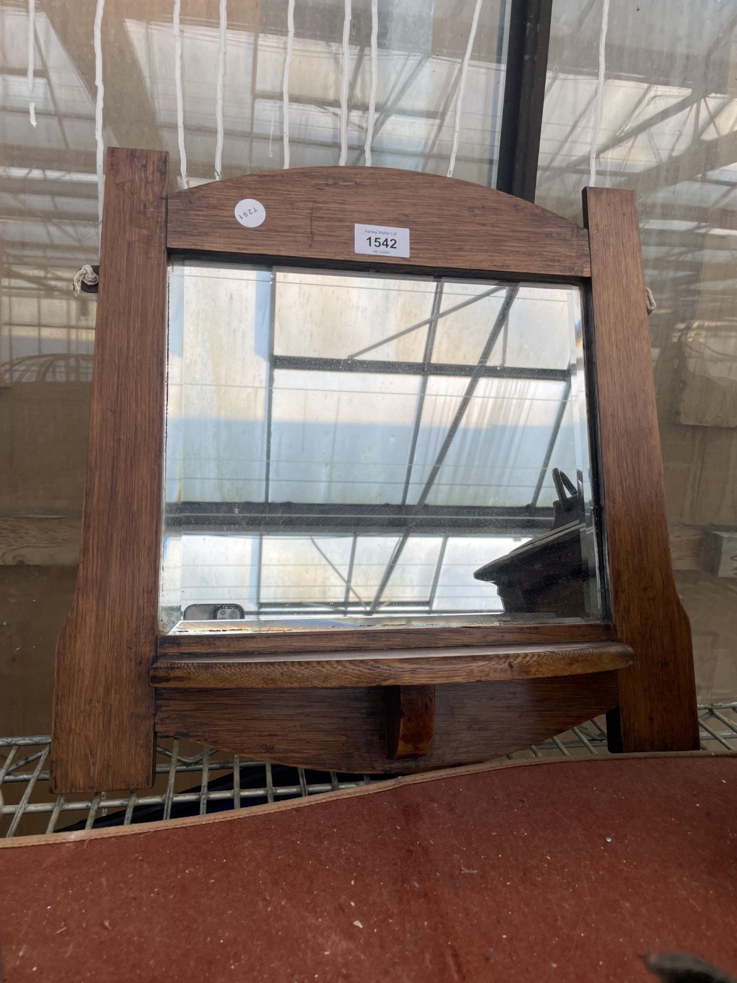 AN OAK FRAMED WALL MIRROR WITH LOWER SHELF