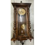A CARVED WALNUT VIENNA WALL CLOCK WITH ROMAN NUMERALS AND PENDULUM