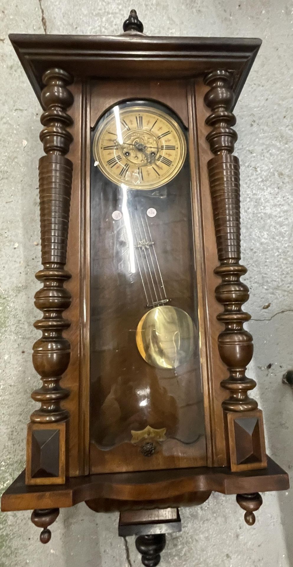 A CARVED WALNUT VIENNA WALL CLOCK WITH ROMAN NUMERALS AND PENDULUM