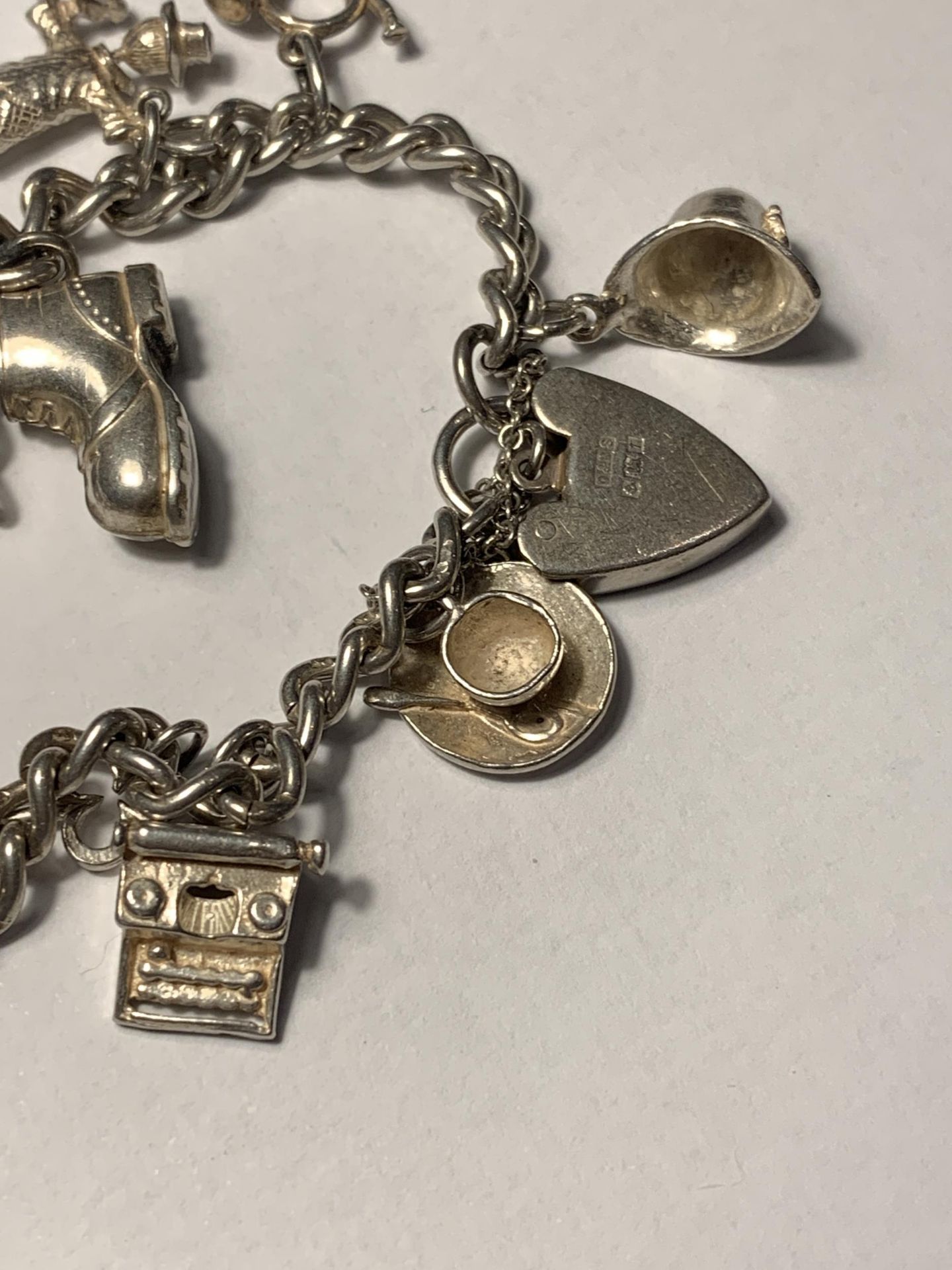 A SILVER CHARM BRACELET WITH ELEVEN CHARMS AND A HALLMARKED BIRMINGHAM SILVER HEART PADLOCK - Image 4 of 4