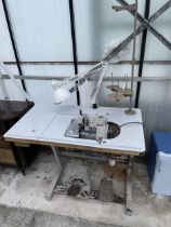 A BROTHER INDUSTRIAL OVERLOCKER SEWING MACHINE WITH TREADLE BASE AND ANGLE POISE LAMP