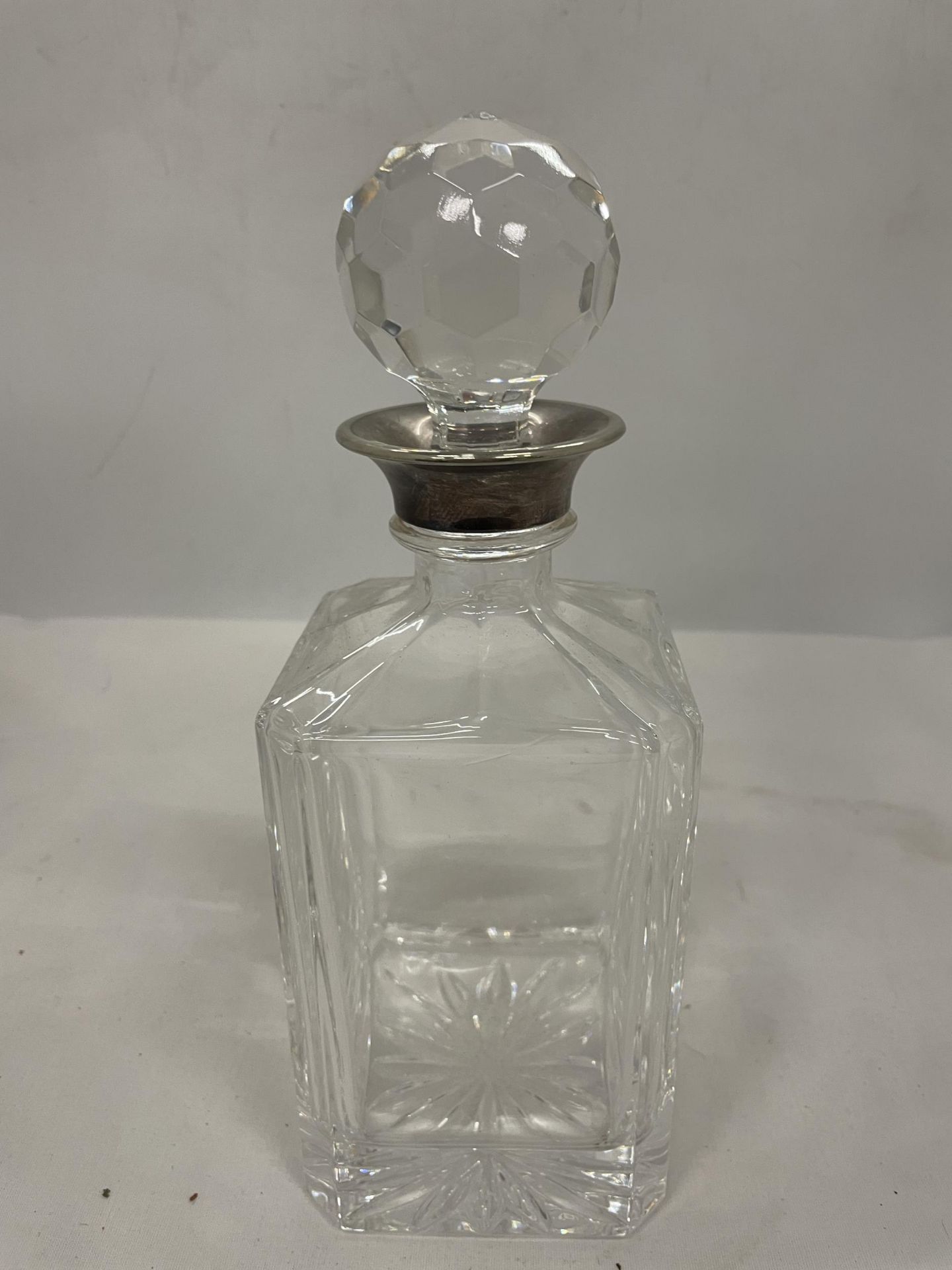 A CUT GLASS DECANTER (STOPPER A/F) WITH A TESTED TO SILVER COLLAR