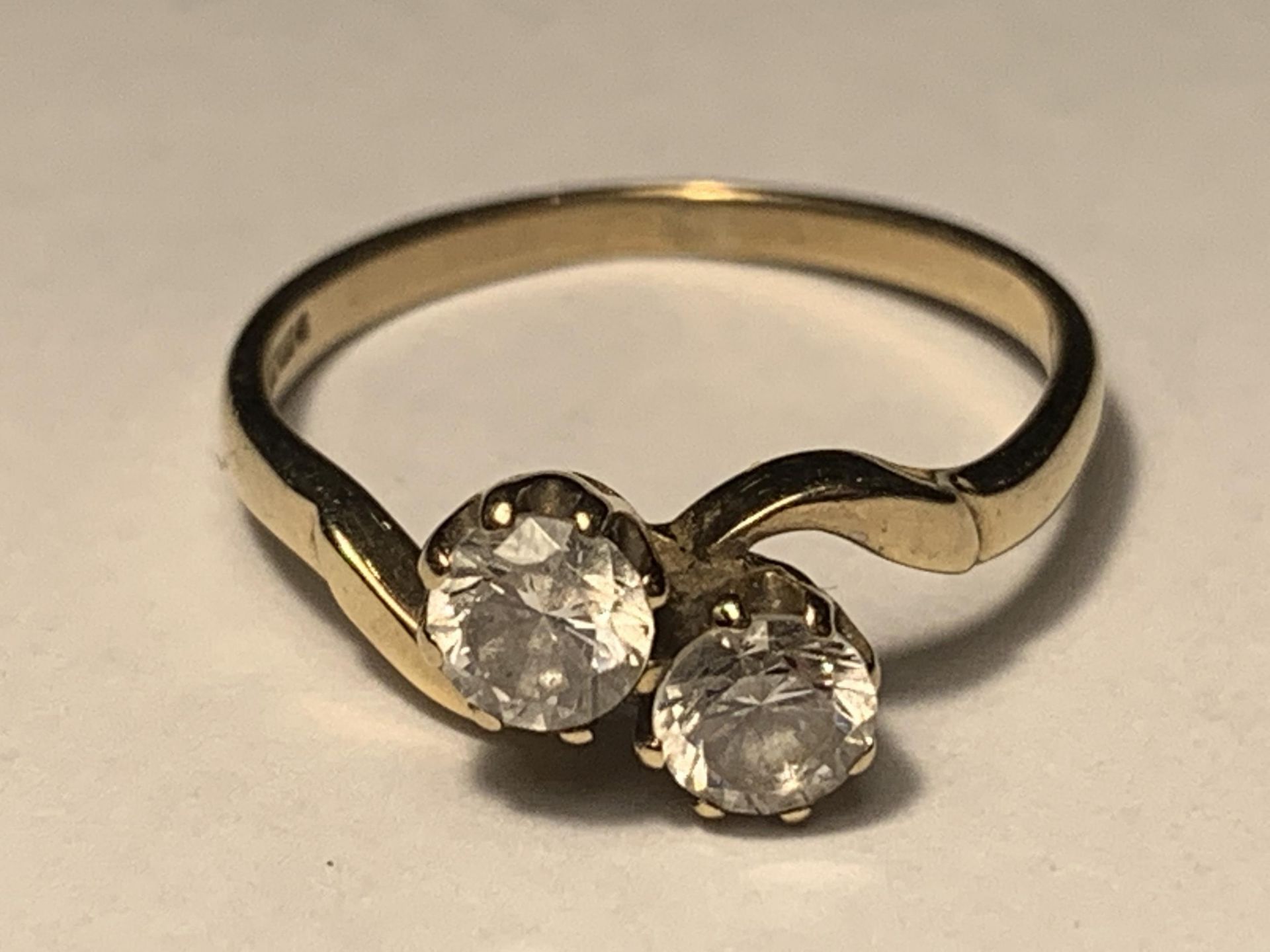 A 9 CARAT GOLD RING WITH TWO CUBIC ZIRCONIAS ON A TWIST DESIGN SIZE J