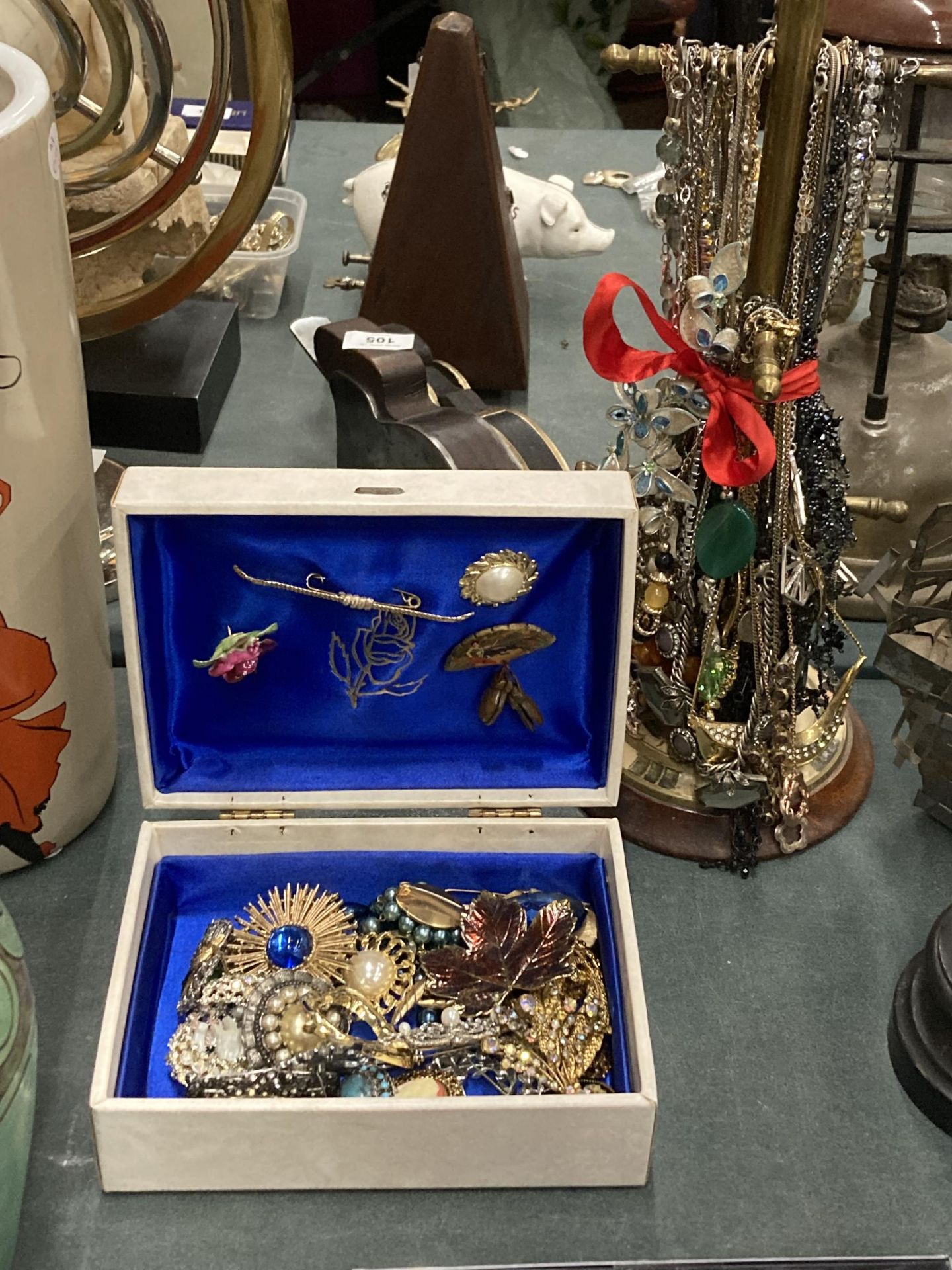 A GROUP OF ASSORTED COSTUME JEWELLERY TO INCLUDE WOODEN DISPLAY STAND AND BOX OF BROOCHES