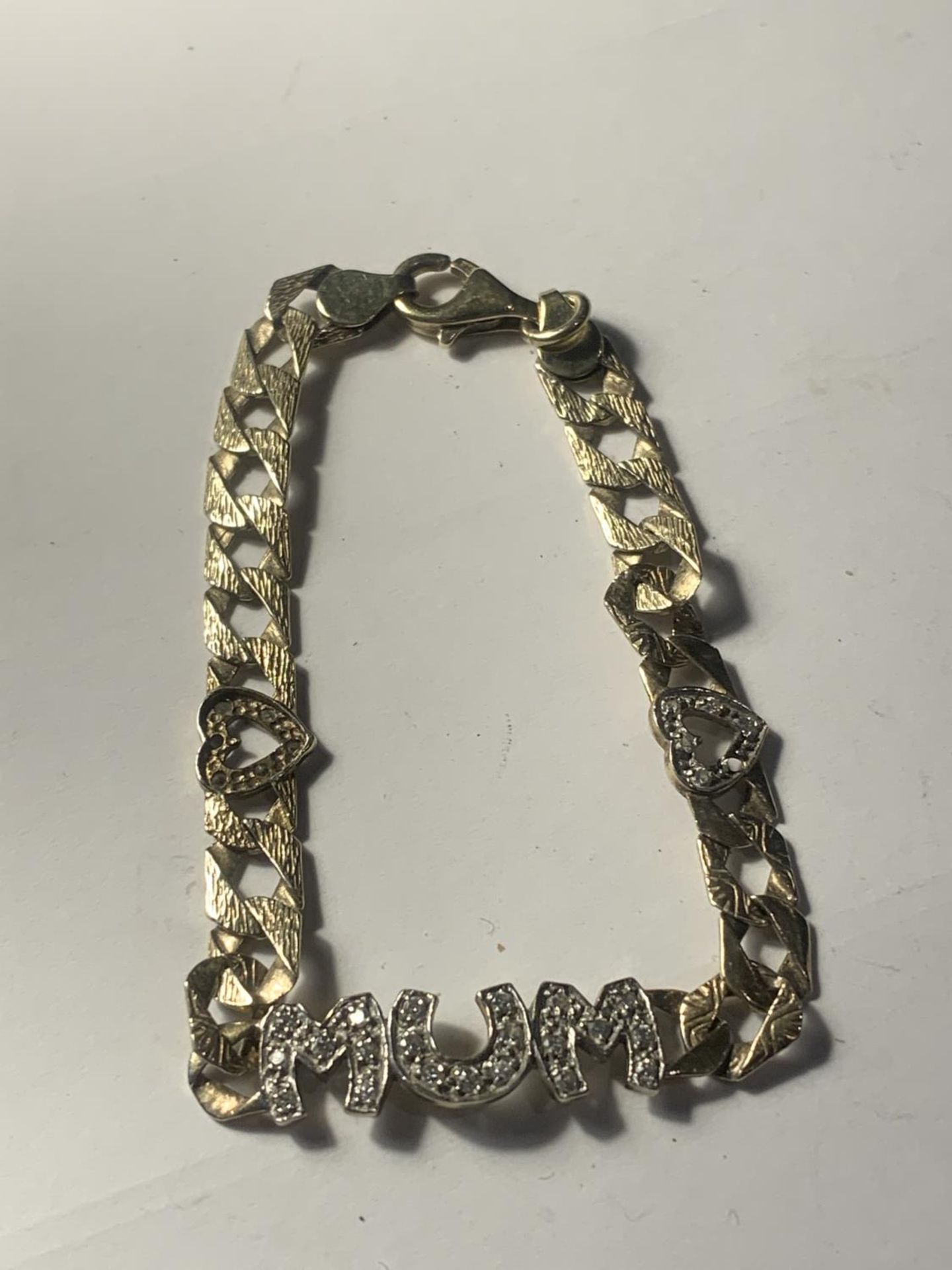 A HEAVY SILVER GILT, STAMPED 925 CURB LINK BRACELET WITH MUM AND TWO HEARTS IN CLEAR STONES