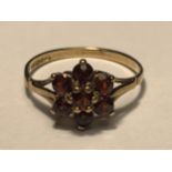 A 9 CARAT GOLD RING WITH SEVEN GARNETS IN A FLOWER DESIGN SIZE M