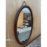 AN OVAL MAHOGANY AND INLAID EDWARDIAN MIRROR