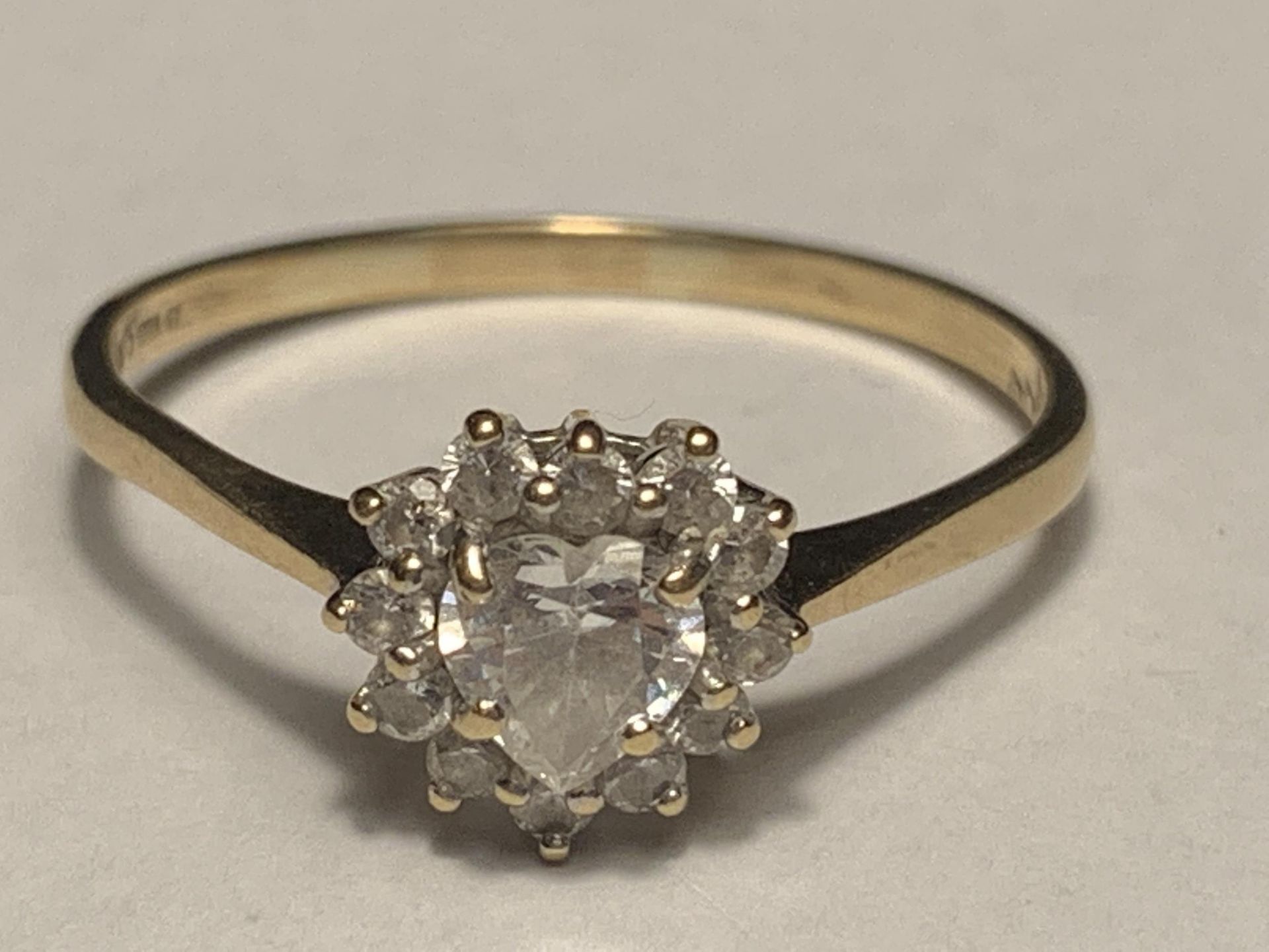 A 9 CARAT GOLD RING WITH A CENTRE HEART DESIGN CUBIC ZIRCONIA SURROUNDED BY THE SAME STONE SIZE T/U