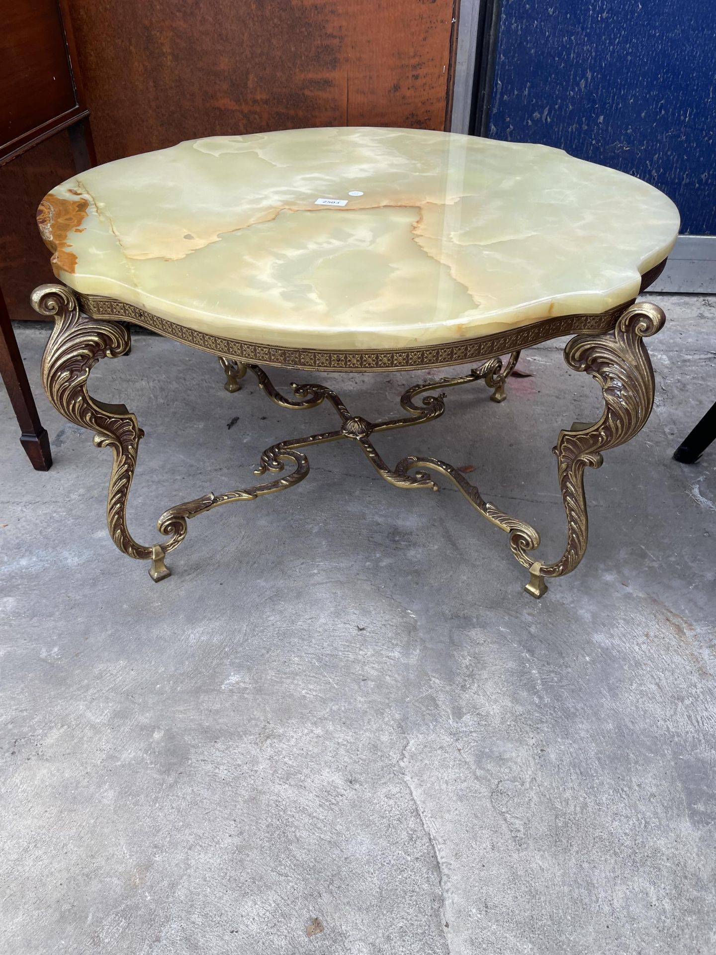 AN ONYX COFFEE TABLE, 34" DIAMETER, ON GILT METALWARE LEGS AND STRETCHERS